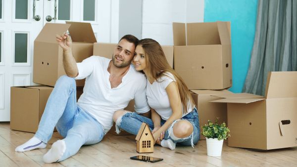 Young couple celebrating their new home with unpacked boxes around.